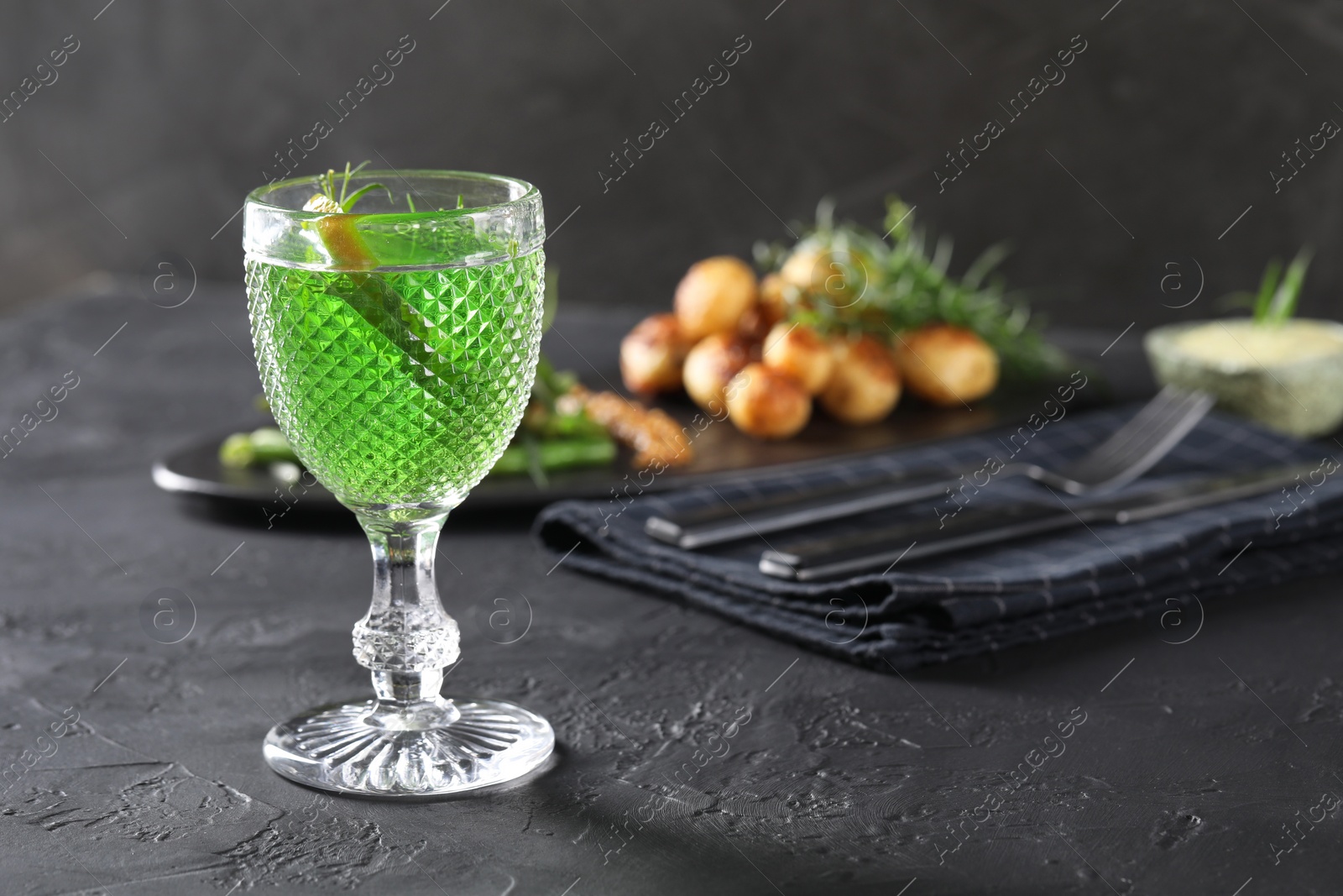 Photo of Delicious drink with tarragon in glass on dark textured table. Space for text