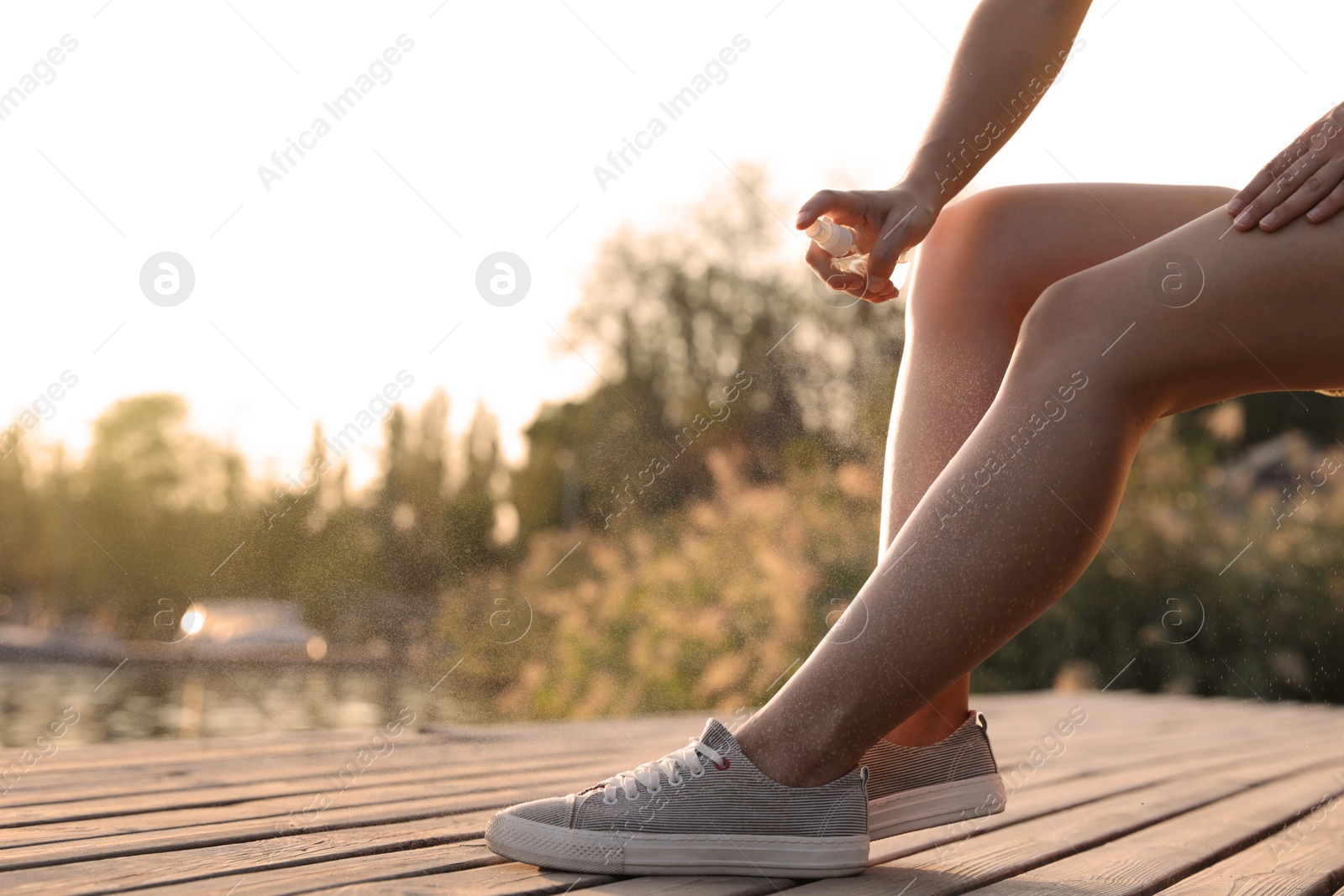 Photo of Woman applying insect repellent onto leg at pier, closeup. Space for text