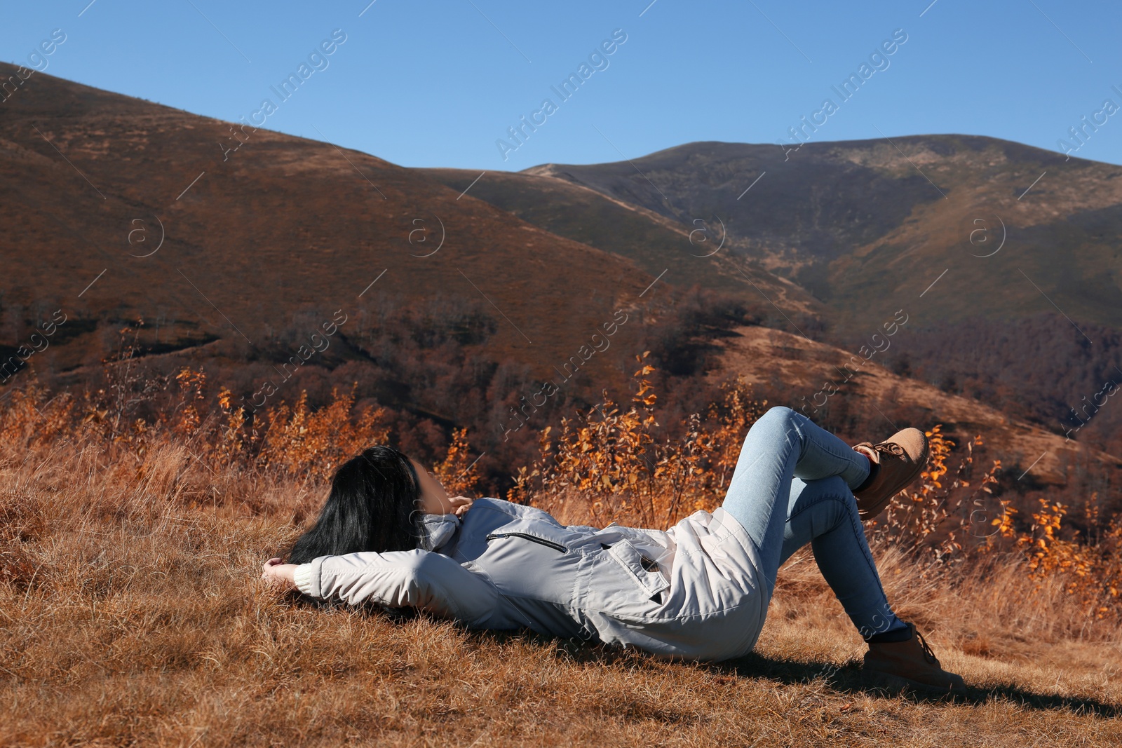 Photo of Woman in warm clothes relaxing on mountain slope