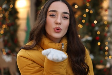 Photo of Portrait of beautiful woman blowing kiss on city street in winter