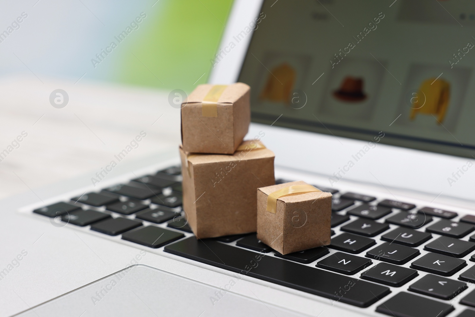 Photo of Internet shopping. Small cardboard boxes on laptop, closeup