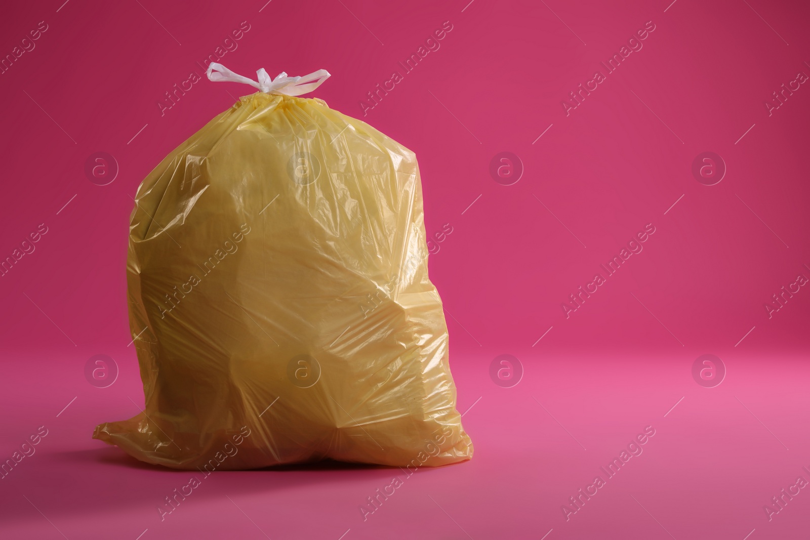 Photo of Trash bag full of garbage on pink background. Space for text