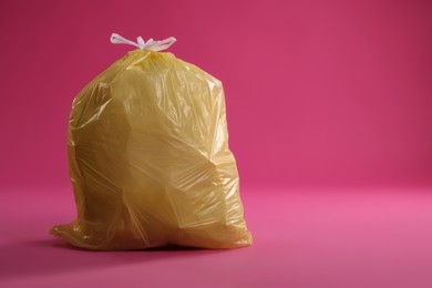 Photo of Trash bag full of garbage on pink background. Space for text