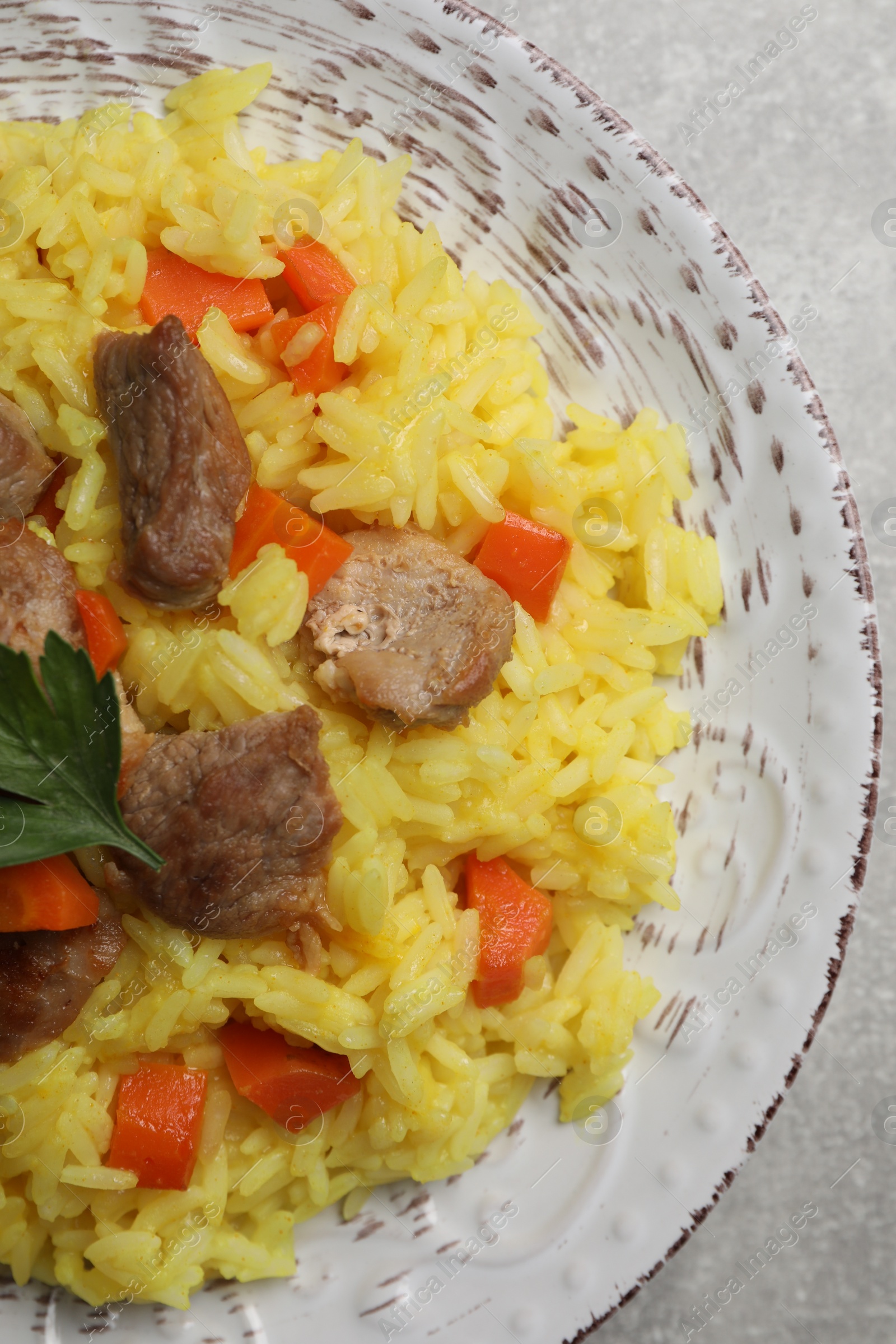 Photo of Delicious pilaf with meat on light grey table, top view