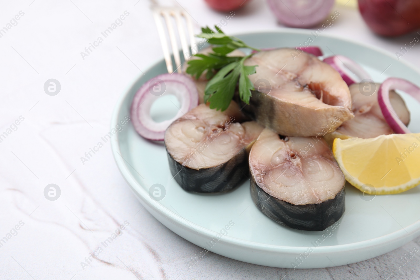 Photo of Slices of tasty salted mackerel with parsley, onion rings and lemon wedge on light textured table, closeup