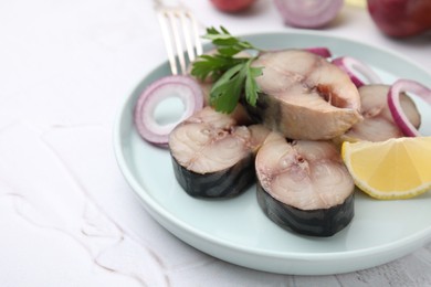 Slices of tasty salted mackerel with parsley, onion rings and lemon wedge on light textured table, closeup