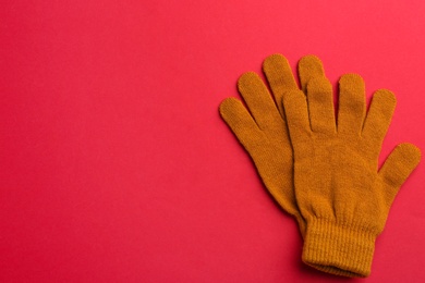 Photo of Pair of stylish woolen gloves on red background, flat lay. Space for text