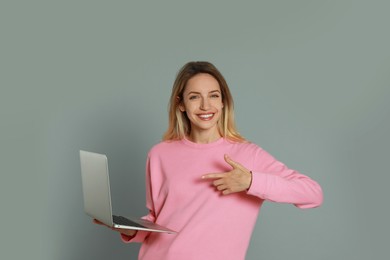 Photo of Young woman with modern laptop on grey background