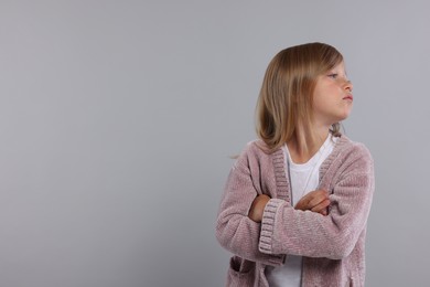 Resentful girl with crossed arms on grey background. Space for text