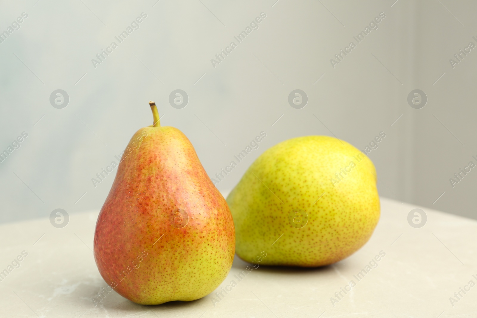 Photo of Ripe juicy pears on stone table against light background