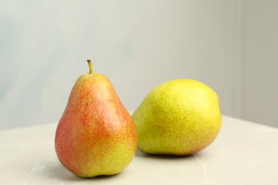 Photo of Ripe juicy pears on stone table against light background