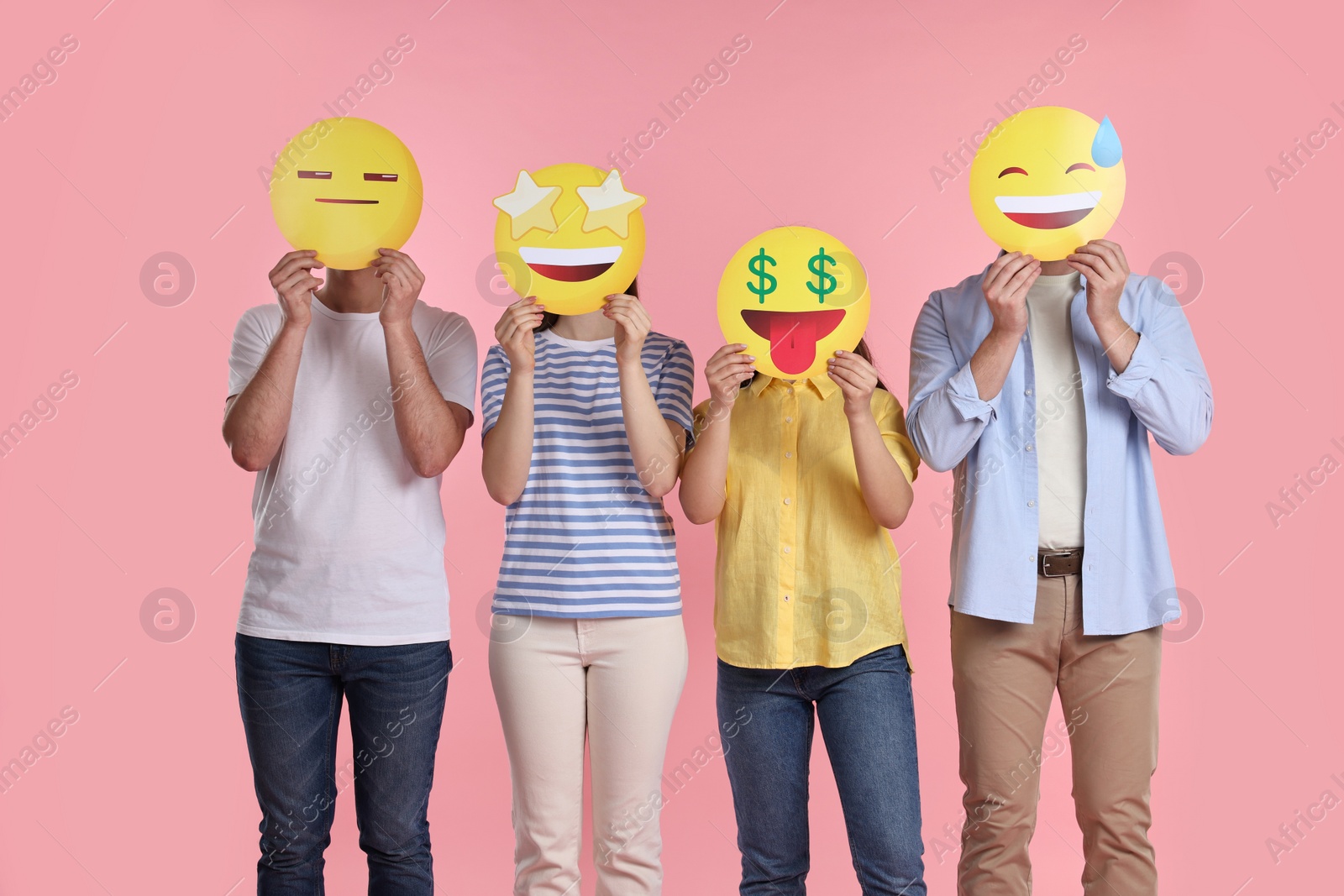 Photo of People covering faces with emoticons on pink background