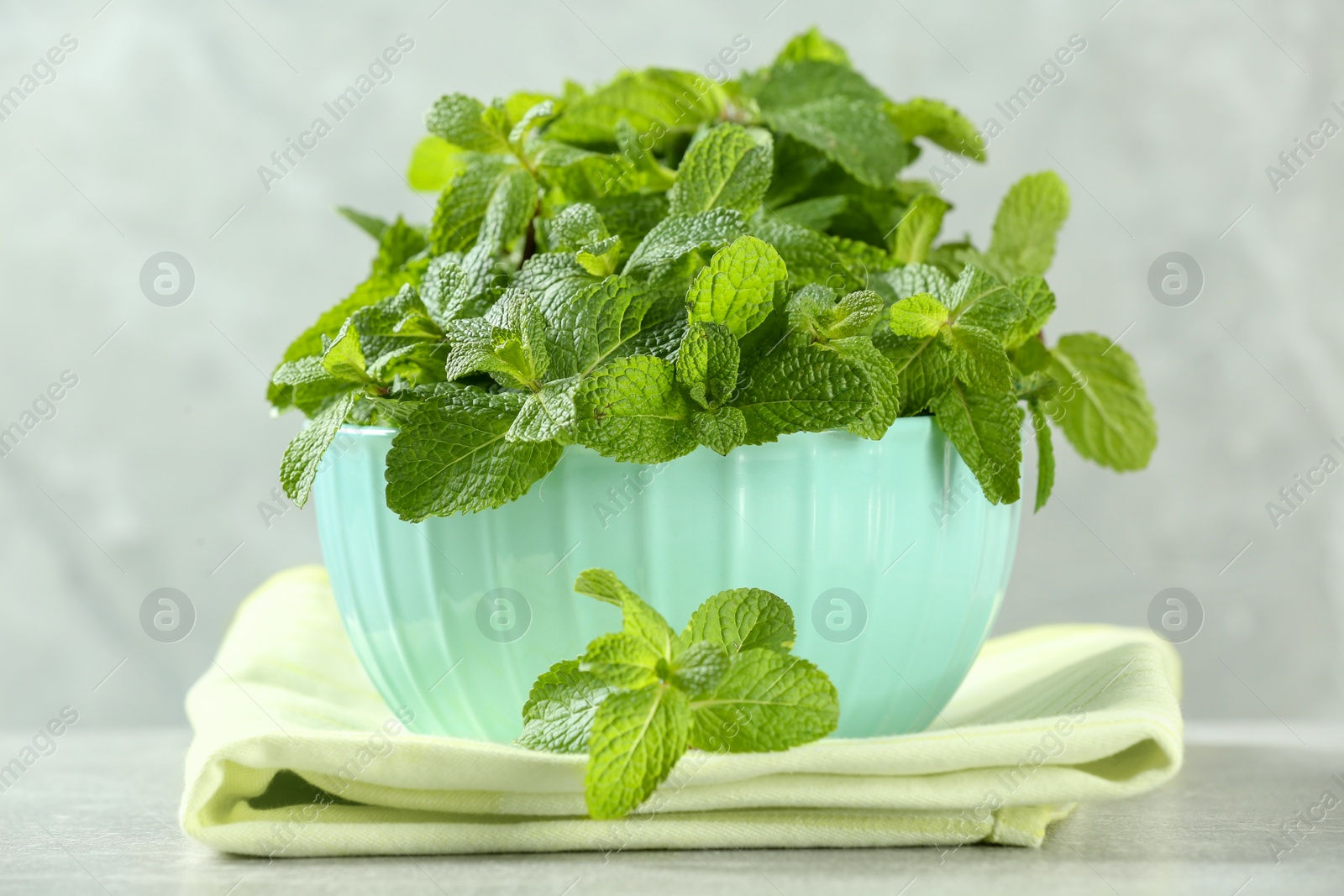 Photo of Bowl with fresh green mint leaves on grey table