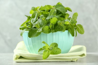 Photo of Bowl with fresh green mint leaves on grey table
