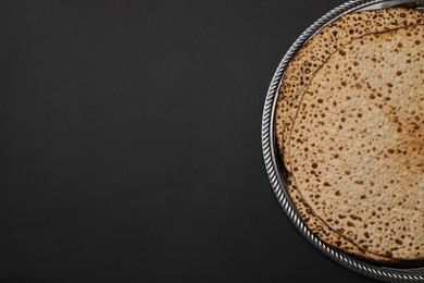 Photo of Tasty matzos on black background, top view with space for text. Passover (Pesach) celebration