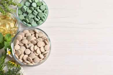 Photo of Different pills, flowers and herbs on white wooden table, flat lay with space for text. Dietary supplements