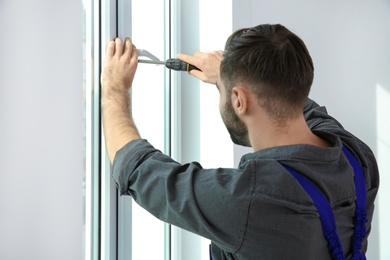 Professional construction worker installing window in apartment