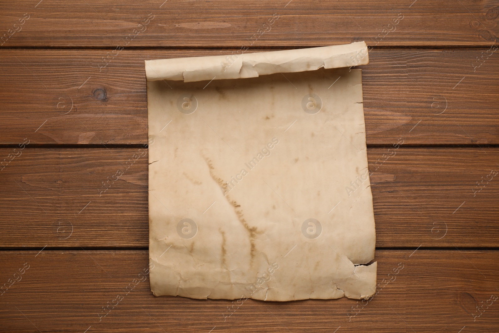 Photo of Sheet of old parchment paper on wooden table, top view. Space for design