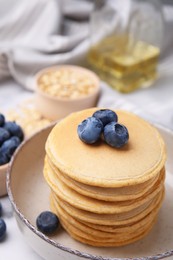Photo of Tasty oatmeal pancakes with blueberries in bowl, closeup
