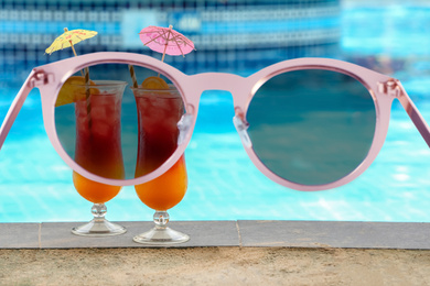 Tasty cocktails near swimming pool, view through sunglasses