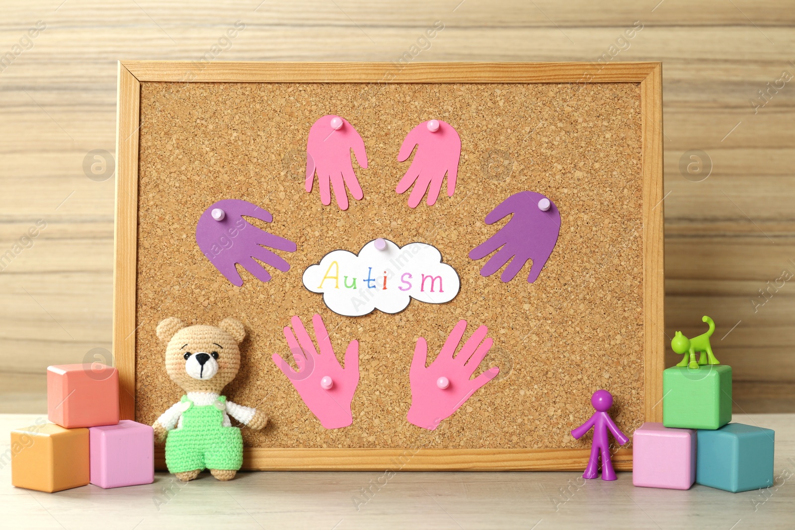 Photo of MYKOLAIV, UKRAINE - DECEMBER 30, 2021: Cork board with word Autism and different toys on wooden table