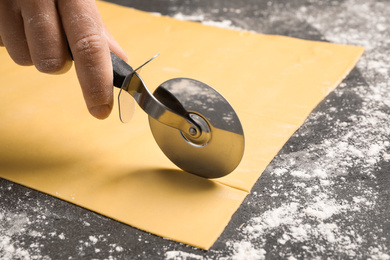 Woman making pasta at grey table, closeup