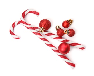 Photo of Tasty candy canes and Christmas balls on white background