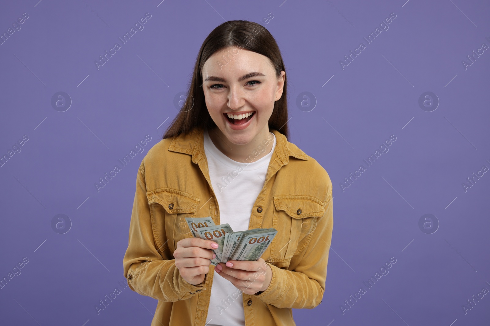 Photo of Happy woman with dollar banknotes on purple background