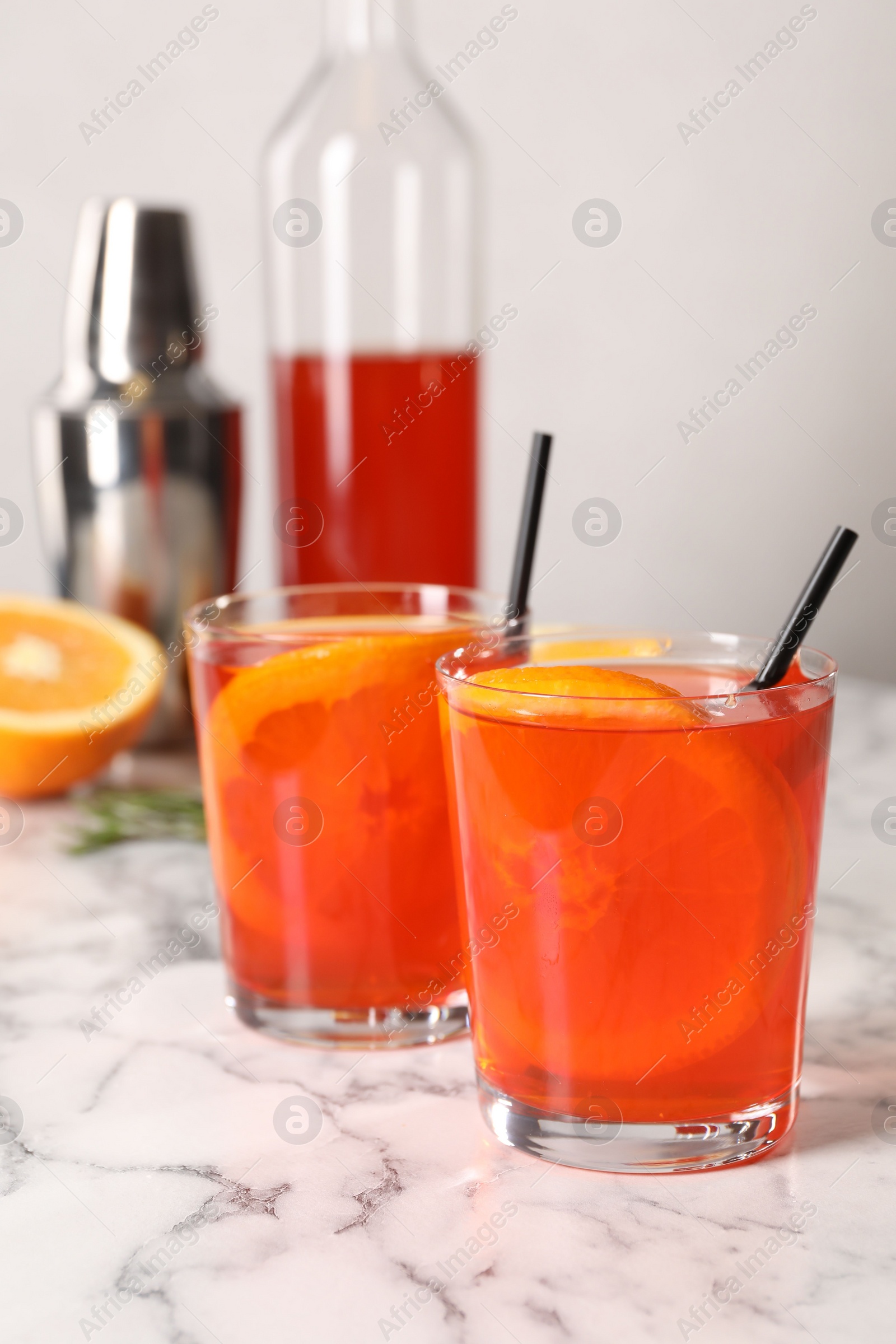 Photo of Aperol spritz cocktail, orange slices and straws in glasses on white marble table