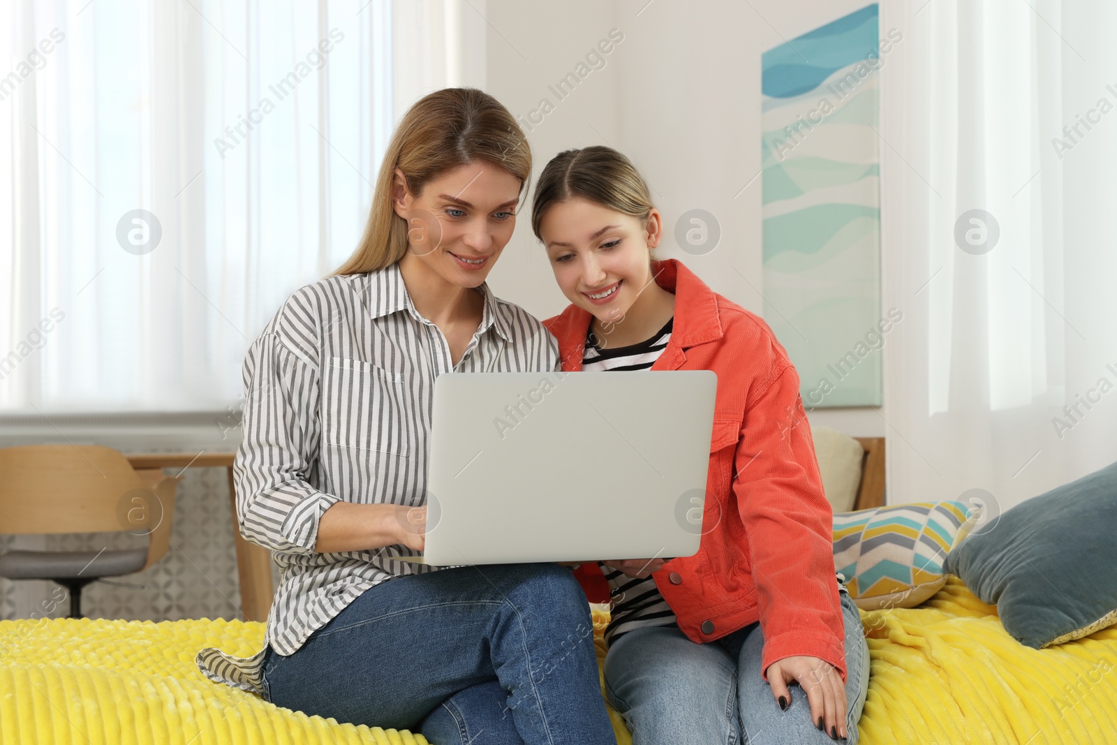 Photo of Happy mother and her teenage daughter with laptop at home