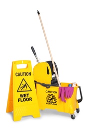 Photo of Safety sign with phrase "CAUTION WET FLOOR" and mop bucket on white background. Cleaning tools