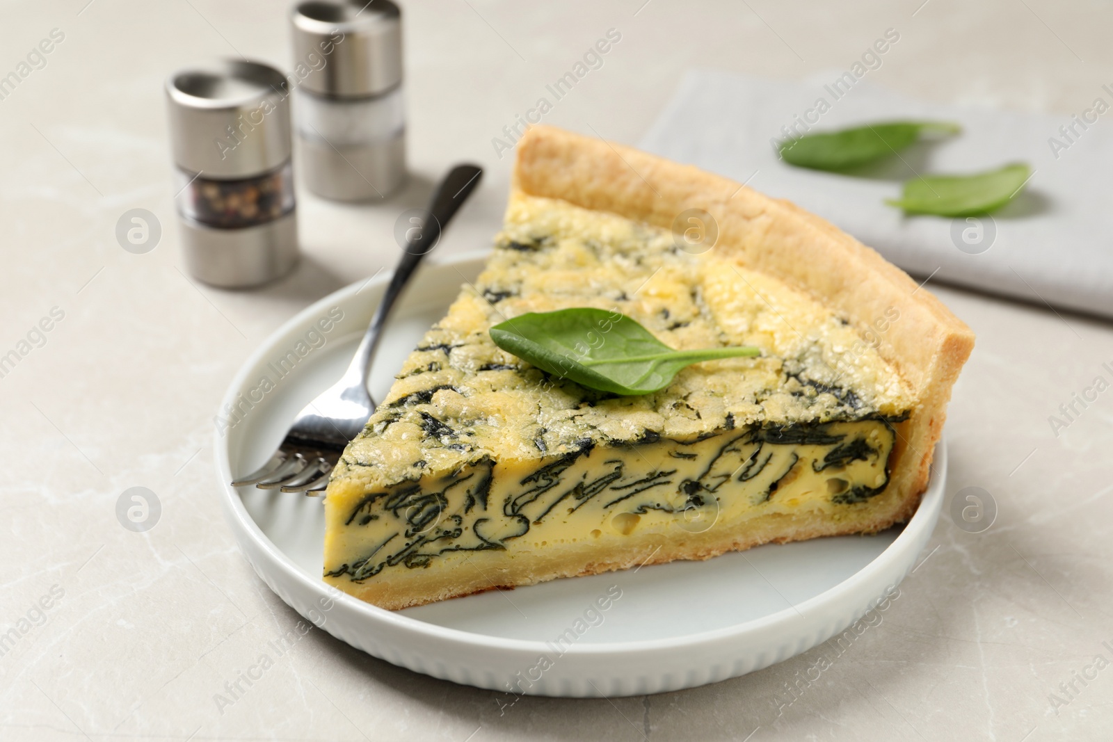 Photo of Piece of delicious spinach pie served on light marble table, closeup