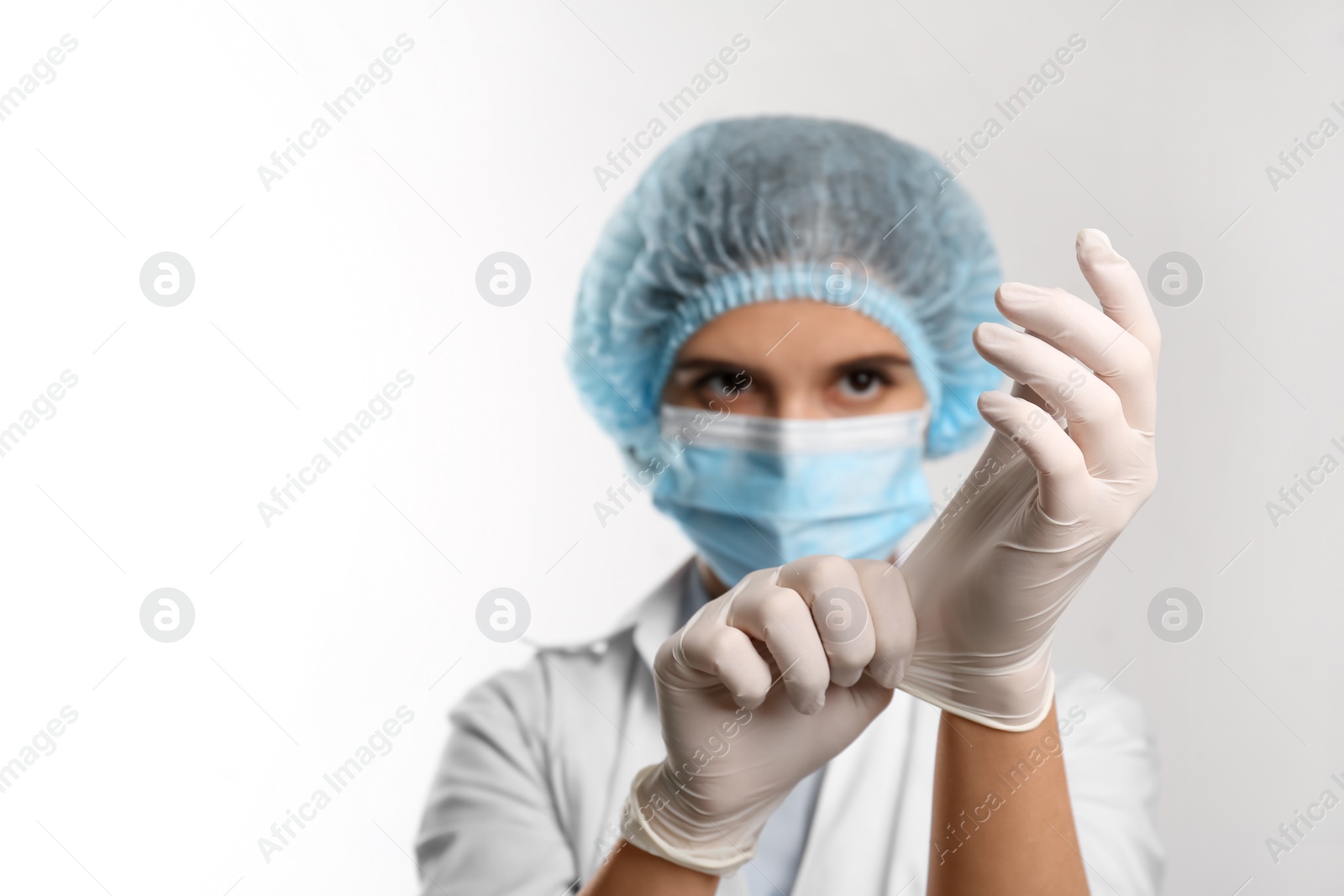 Photo of Doctor putting on medical protective glove against white background