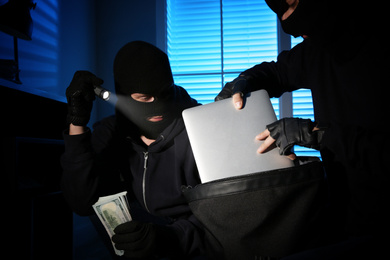 Photo of Thieves taking money and laptop out of steel safe indoors at night