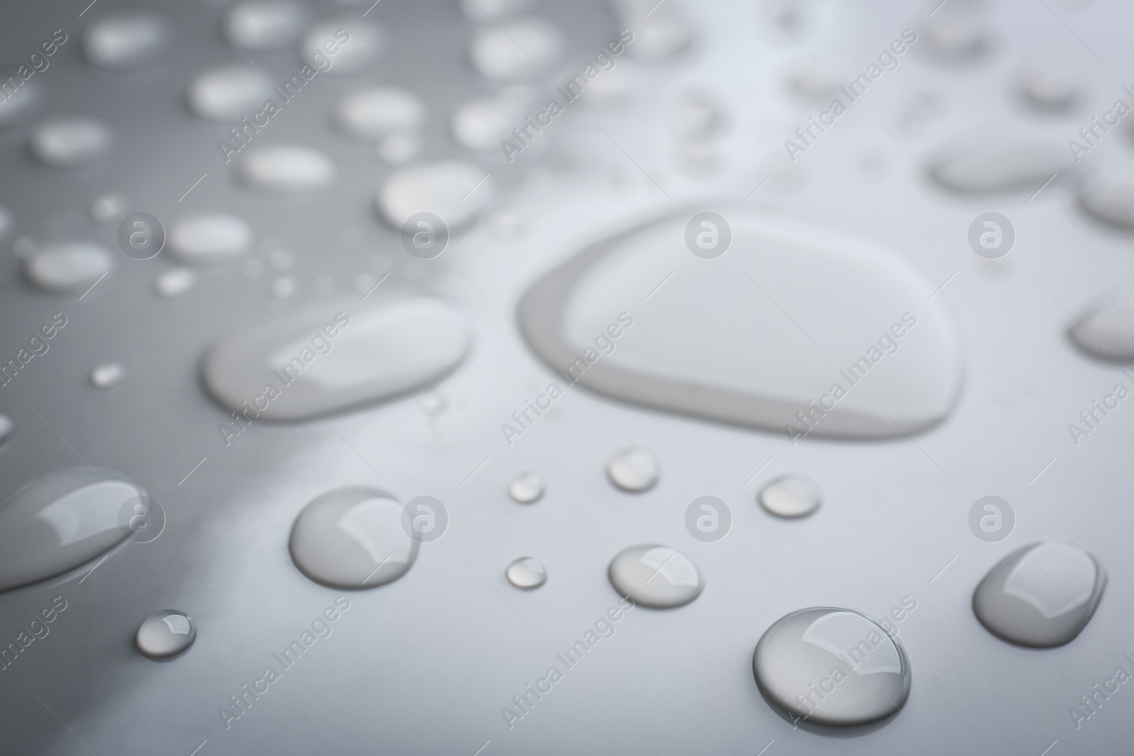 Photo of Drops of spilled water on grey background, closeup