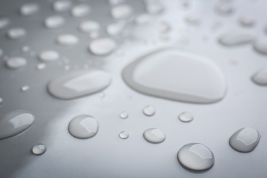 Drops of spilled water on grey background, closeup