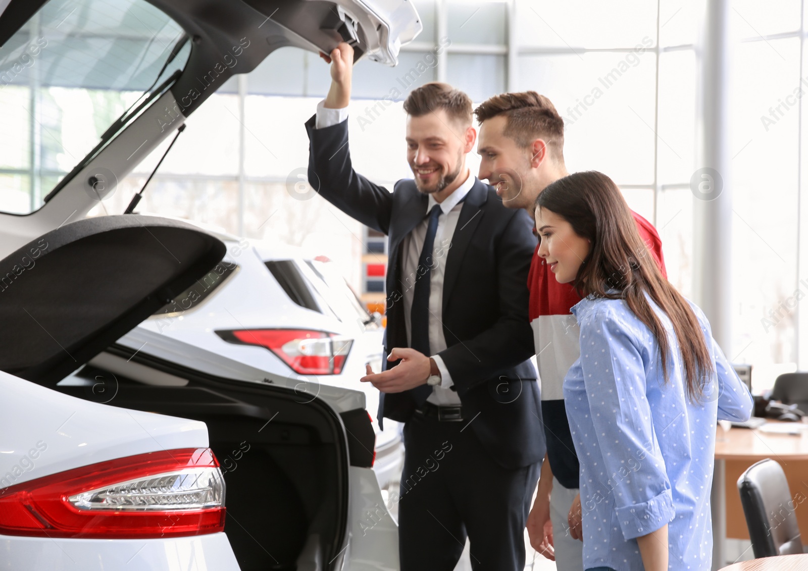 Photo of Young couple buying new car in salon