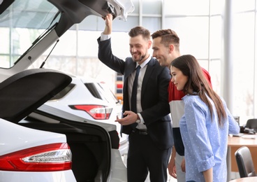 Photo of Young couple buying new car in salon