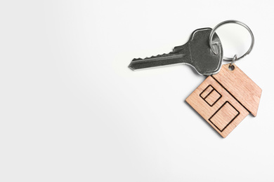 Photo of Key with trinket in shape of house isolated on white, top view. Real estate agent services