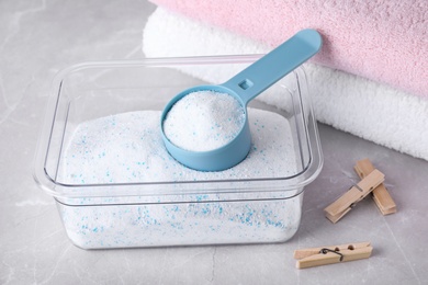 Photo of Laundry powder, clothespins and clean towels on marble table