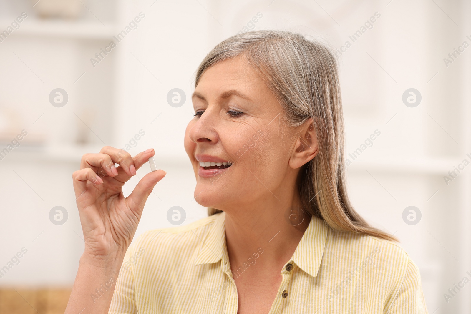 Photo of Menopause, hormone replacement therapy. Happy woman taking pill at home