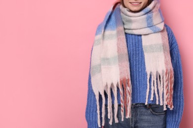 Photo of Woman in warm scarf on pink background, closeup. Space for text