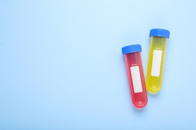 Photo of Test tubes with colorful liquids on light blue background, flat lay and space for text. Kids chemical experiment set