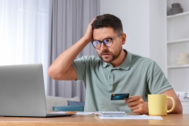Man with credit card using laptop for paying taxes online at home