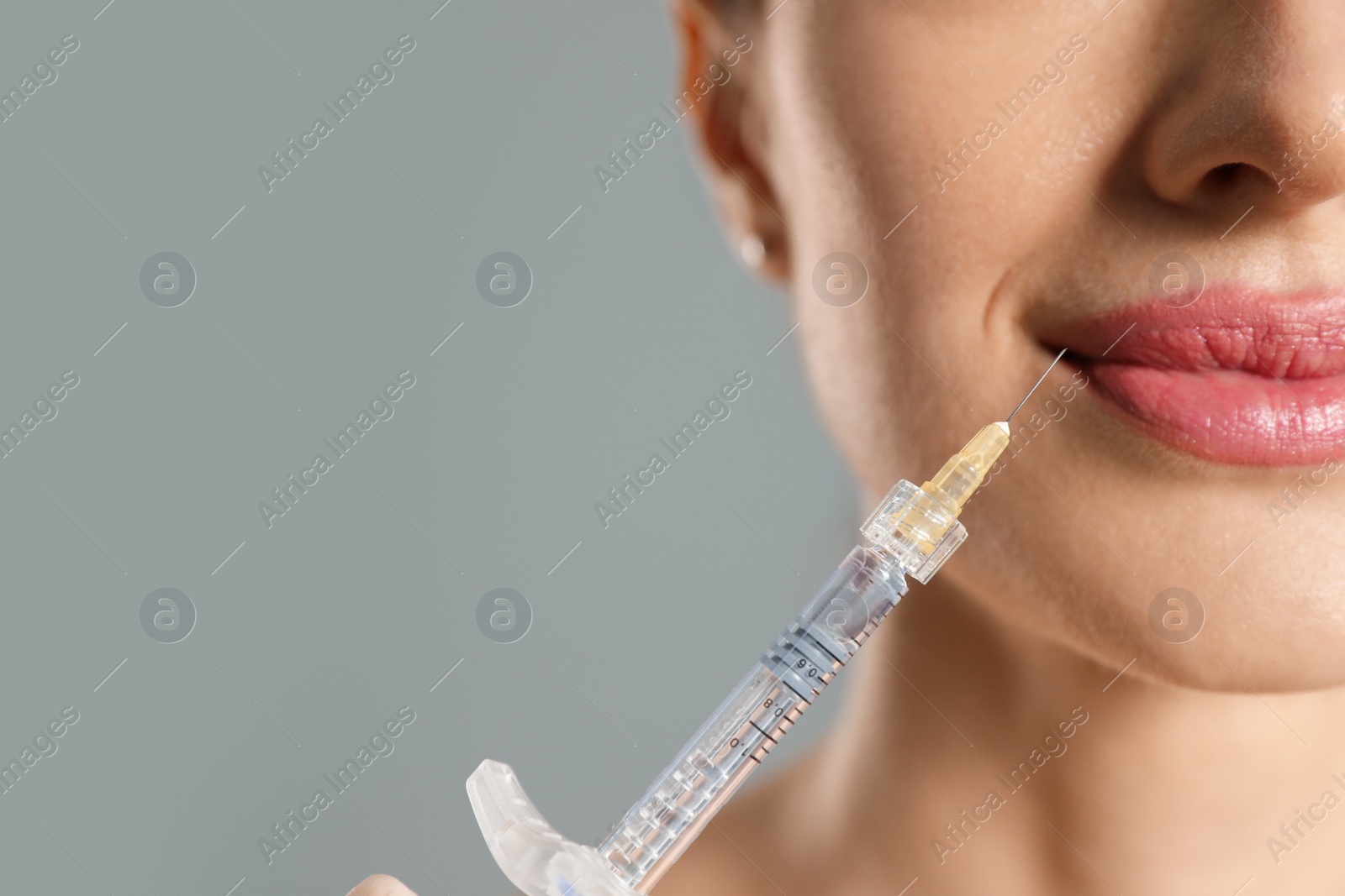 Photo of Beautiful woman getting facial injection on grey background, closeup. Cosmetic surgery