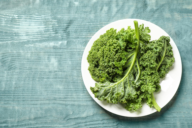 Photo of Fresh kale leaves on light blue wooden table, top view. Space for text