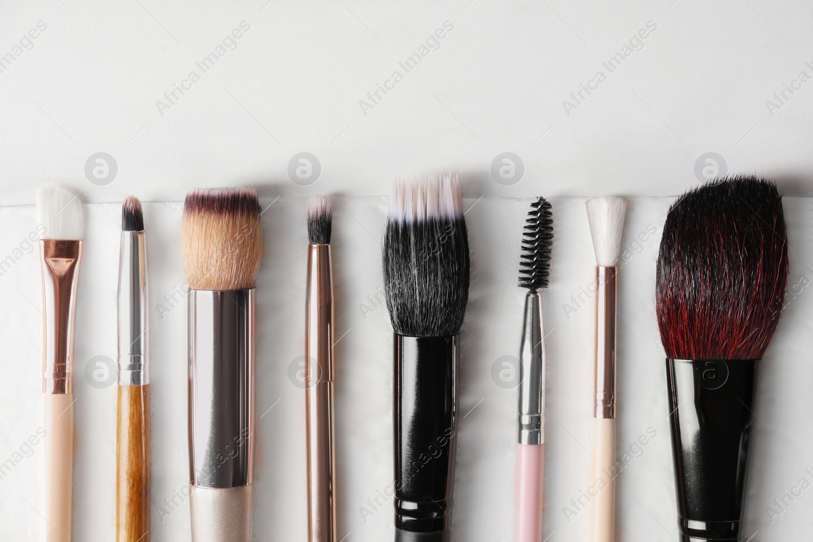 Photo of Set of different makeup brushes drying after cleaning on white table, flat lay. Space for text