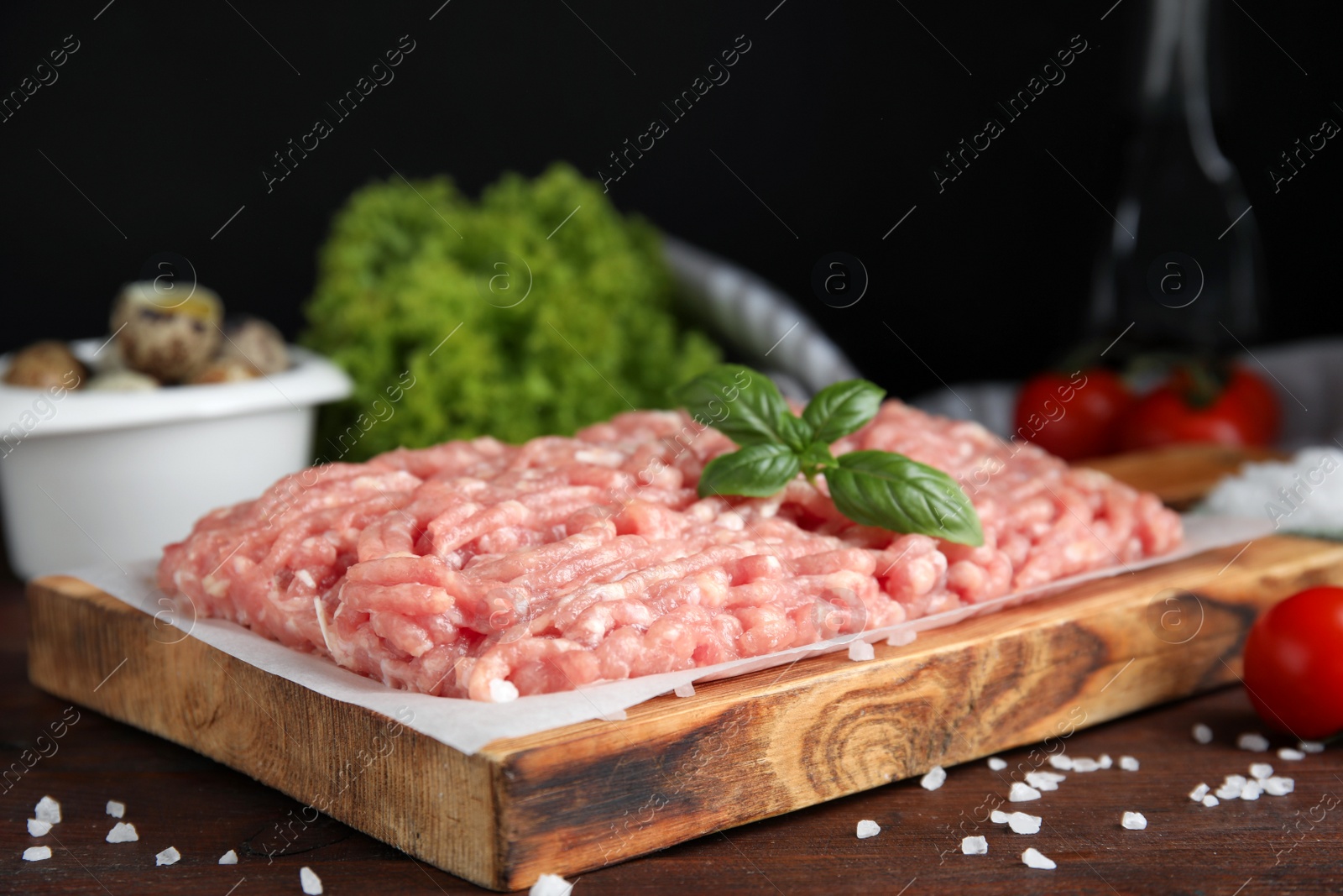 Photo of Raw chicken minced meat with basil and salt on wooden table, closeup