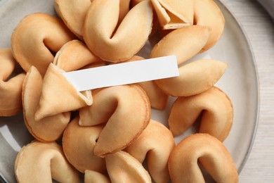 Photo of Tasty fortune cookies and paper with prediction on wooden table, top view. Space for text
