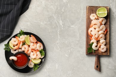 Photo of Tasty boiled shrimps with cocktail sauce, parsley and lime on light grey table, flat lay. Space for text